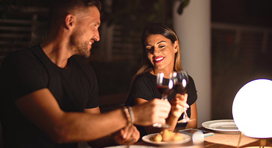 young beautiful couple dinning on celebration toasting and smiling at terrace